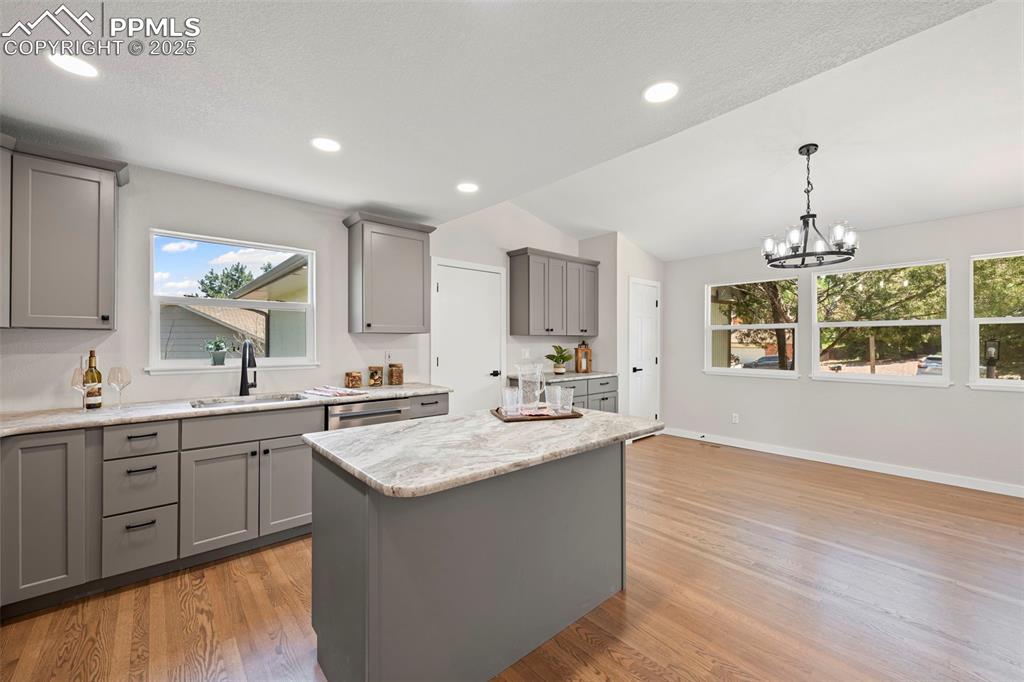 Image 6 of 48: Kitchen with gray cabinetry, plenty of natural light, light wood finished f