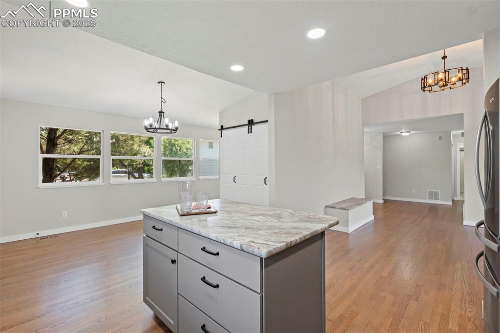 Image 7 of 48: Kitchen with a chandelier, vaulted ceiling, freestanding refrigerator, gray