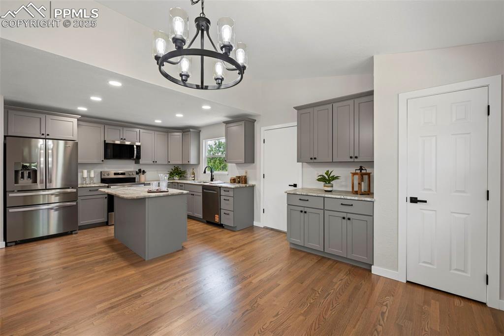 Image 8 of 48: Kitchen featuring stainless steel appliances, gray cabinetry, a chandelier,