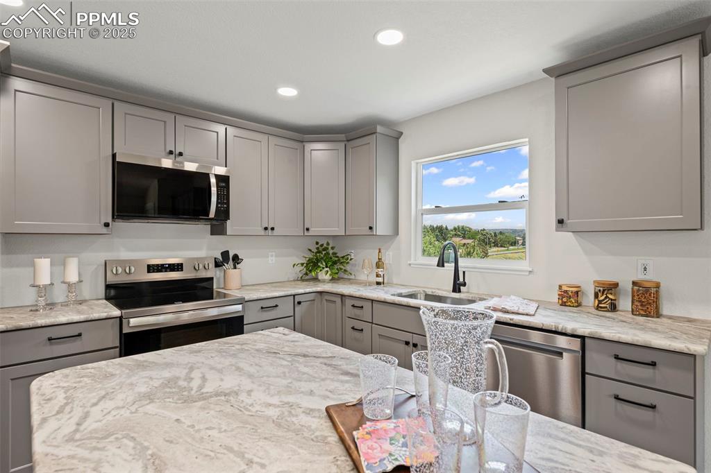 Image 9 of 48: Kitchen with appliances with stainless steel finishes, gray cabinetry, rece