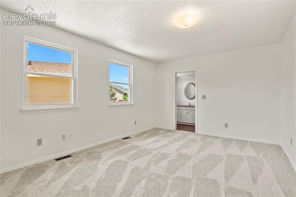 Image 12 of 33: Main level primary bedroom, new carpet!