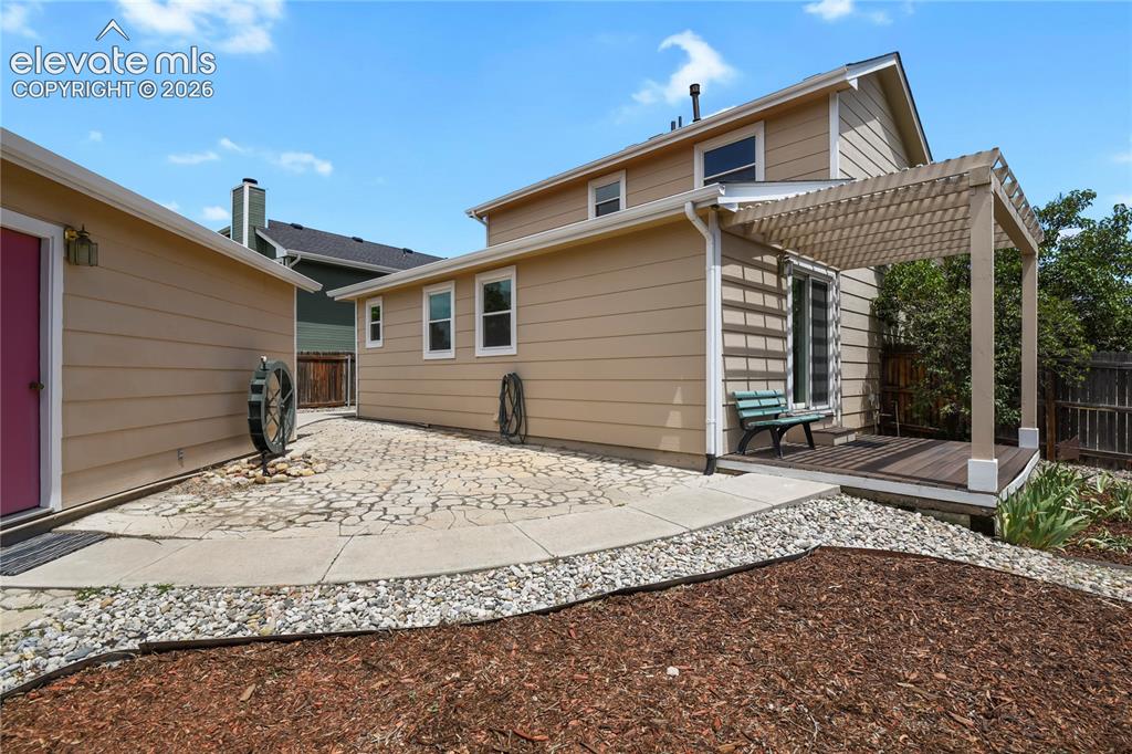 Image 27 of 33: Low-maintenance backyard with mature landscaping and flagstone patio areas