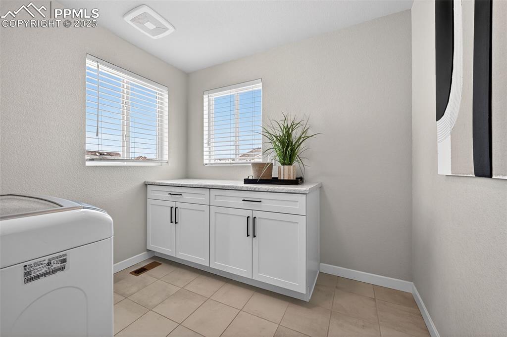 Image 26 of 43: Large laundry room with big windows and folding station
