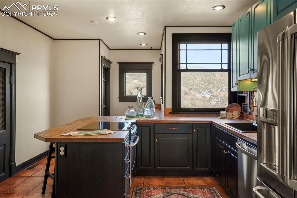 Image 28 of 47: Kitchen with tile floors, a kitchen breakfast bar, recessed lighting.  Corn