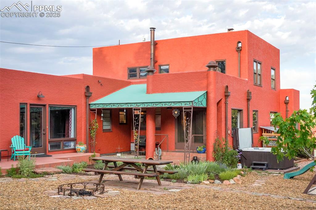 Image 3 of 47: Back of property featuring a patio area, stucco siding, a hot tub, and an o