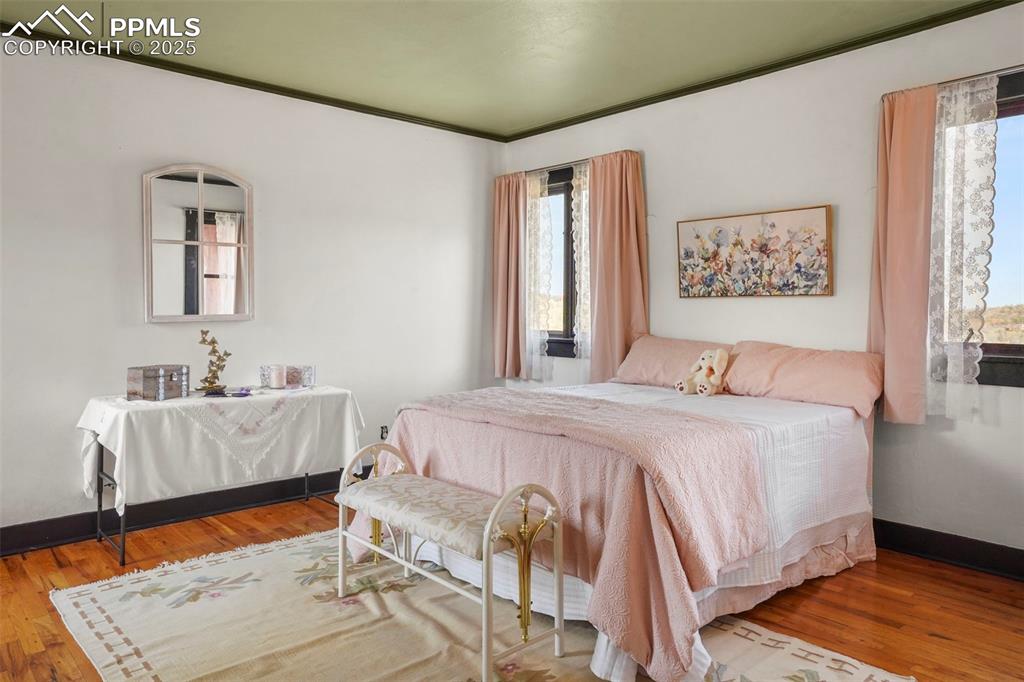 Image 42 of 47: Primary upstairs bedroom featuring baseboards, ornamental molding, and wood