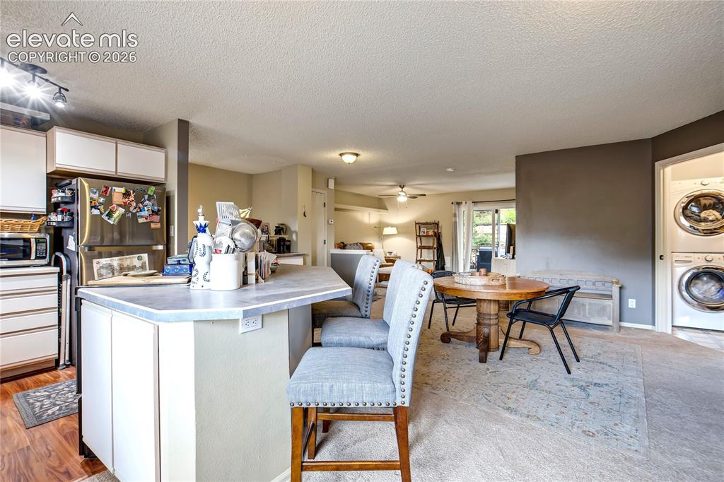 Image 11 of 50: Kitchen island with white cabinetry and an extended countertop, stainless s