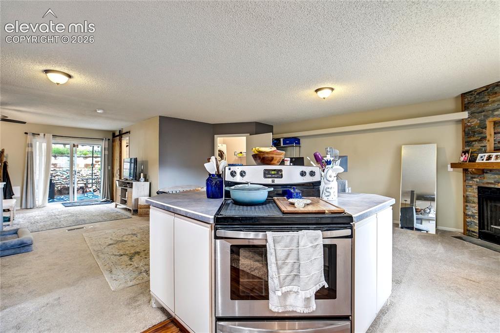 Image 12 of 50: Kitchen island with integrated stainless steel range and oven, stone firepl