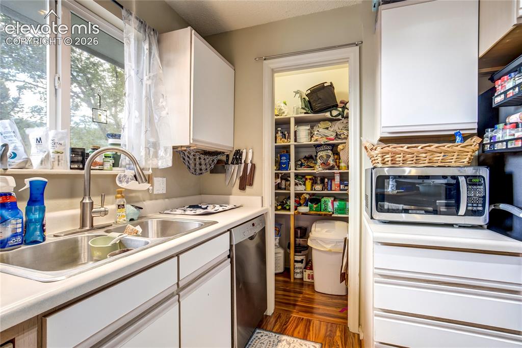 Image 14 of 50: White cabinetry, stainless steel double basin sink, and wood-finish floorin