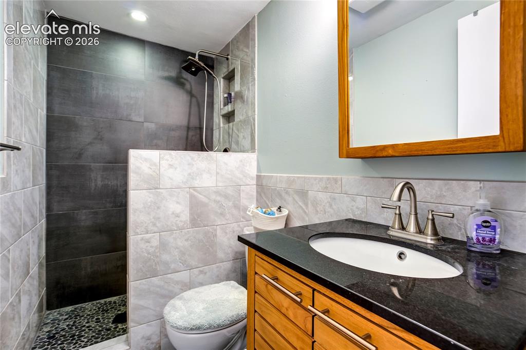 Image 18 of 50: Walk-in shower with dark large-format tile and a pebble floor