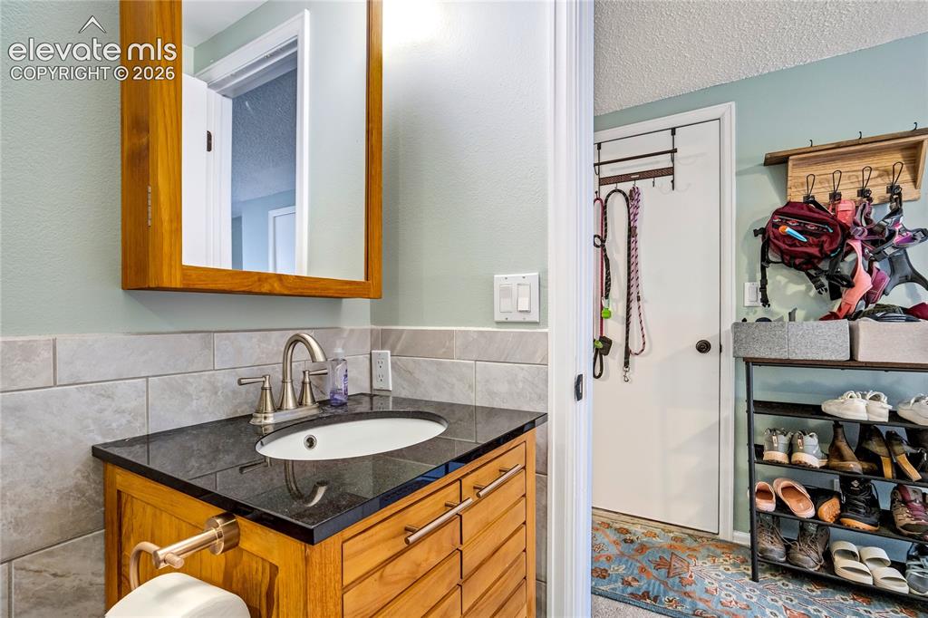 Image 19 of 50: Wood-finish vanity with a black countertop and an undermount sink