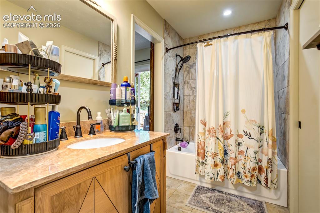 Image 21 of 50: Bathroom featuring a single vanity with a natural stone countertop, undermo