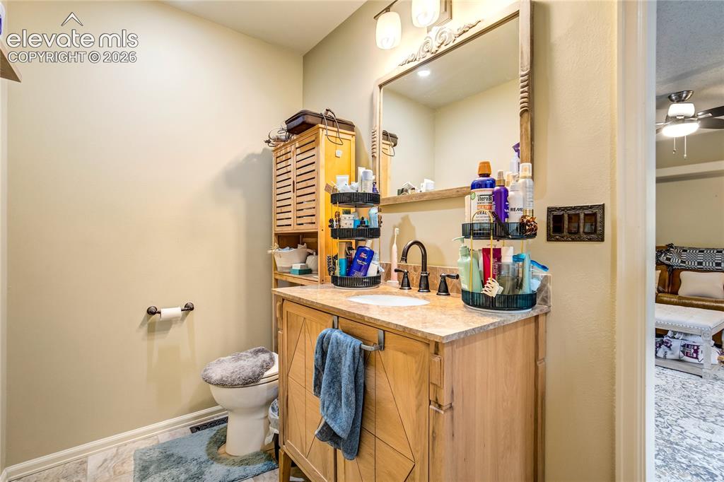 Image 22 of 50: Single vanity with a stone-finish countertop, wood-finish cabinetry, and an