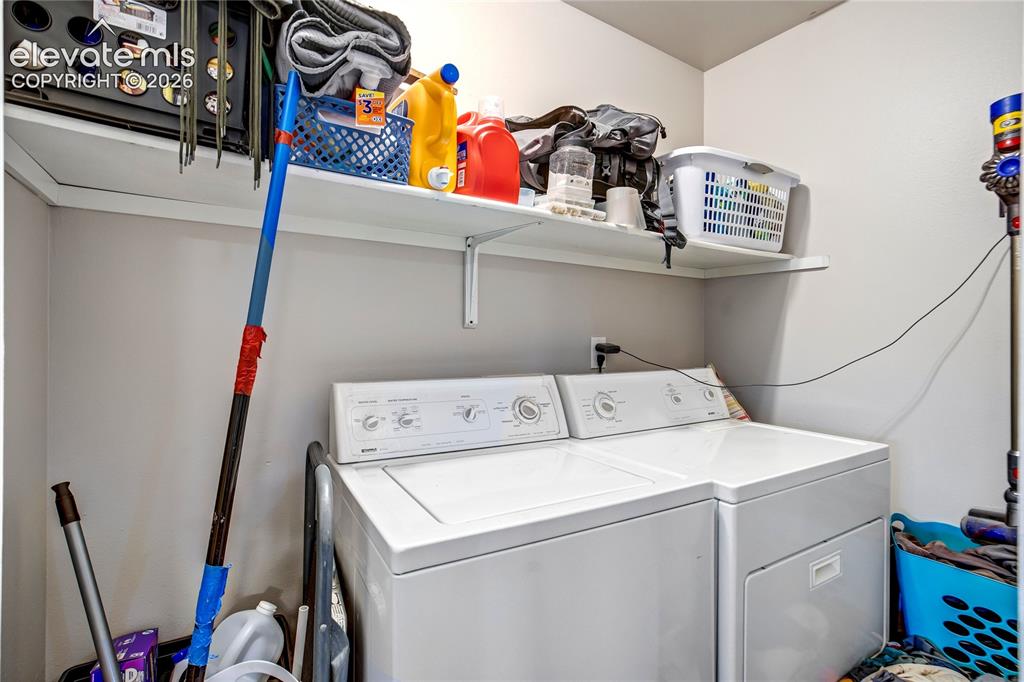 Image 25 of 50: Dedicated laundry area featuring a washer and dryer, built-in shelving, and