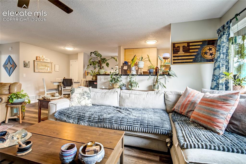 Image 30 of 50: Open-concept living area with wood-finish flooring, a ceiling fan, recessed