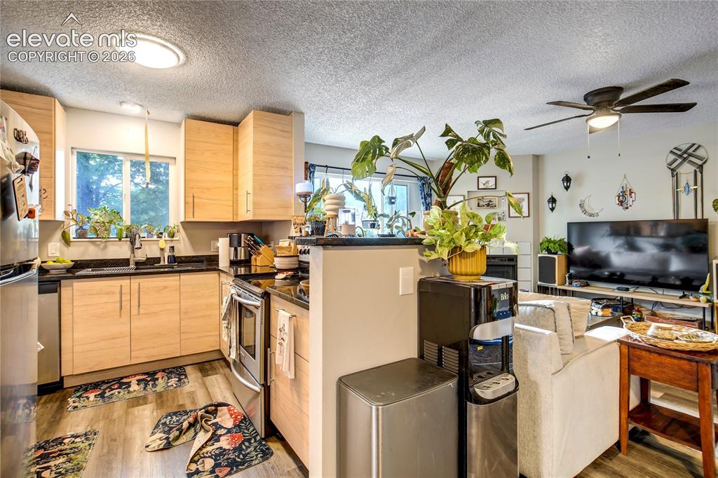 Image 32 of 50: Kitchen featuring light wood-finish cabinetry, black countertops, and stain