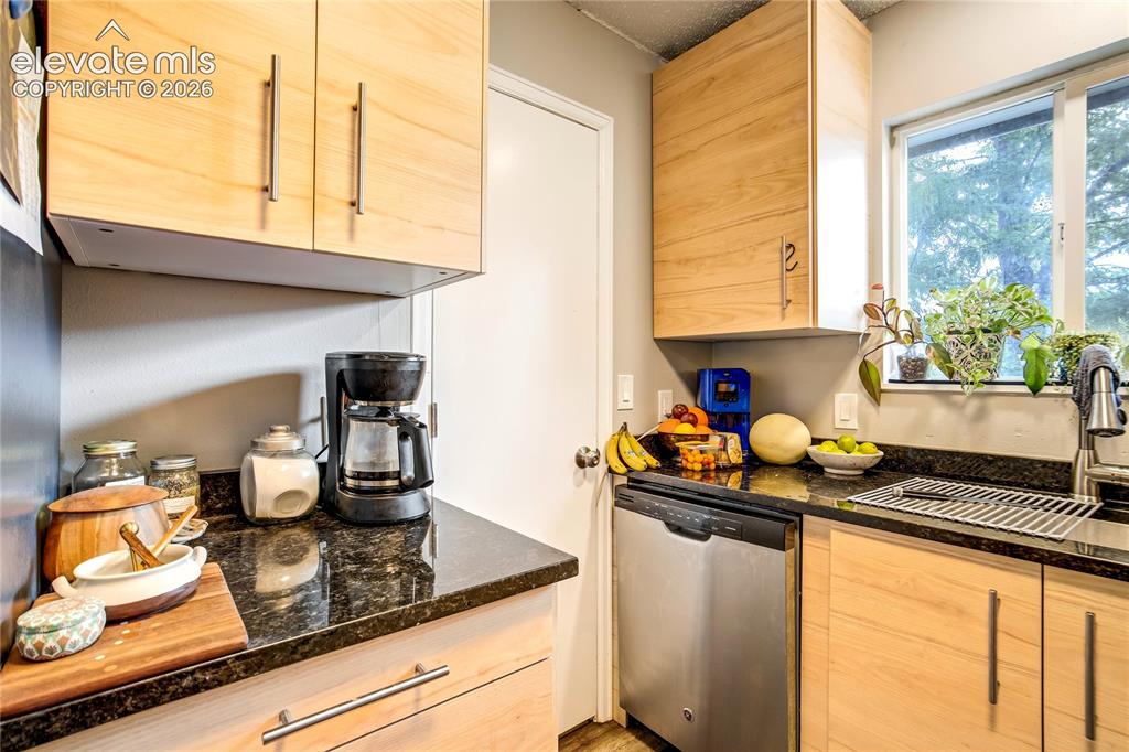 Image 33 of 50: Wood-finish cabinetry with modern hardware, black countertop, stainless ste