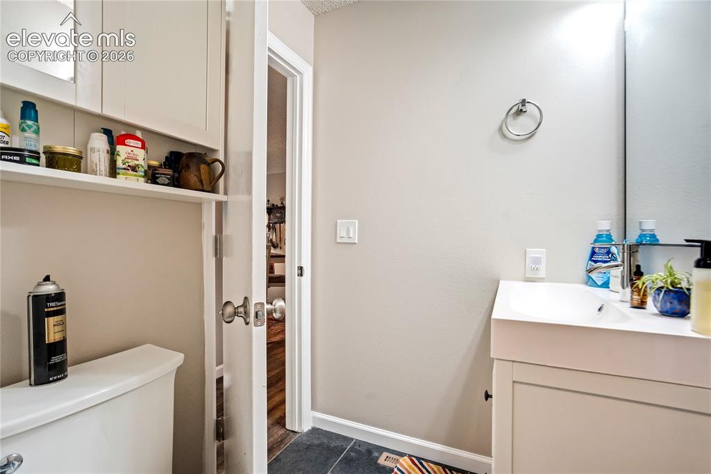Image 40 of 50: White vanity with integrated sink, chrome towel ring, wall-mounted mirror,