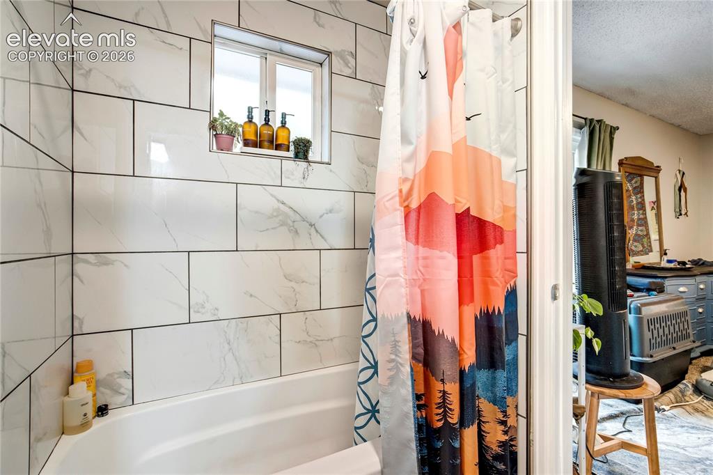 Image 41 of 50: Bathtub with white subway tile surround, integrated window, and recessed sh