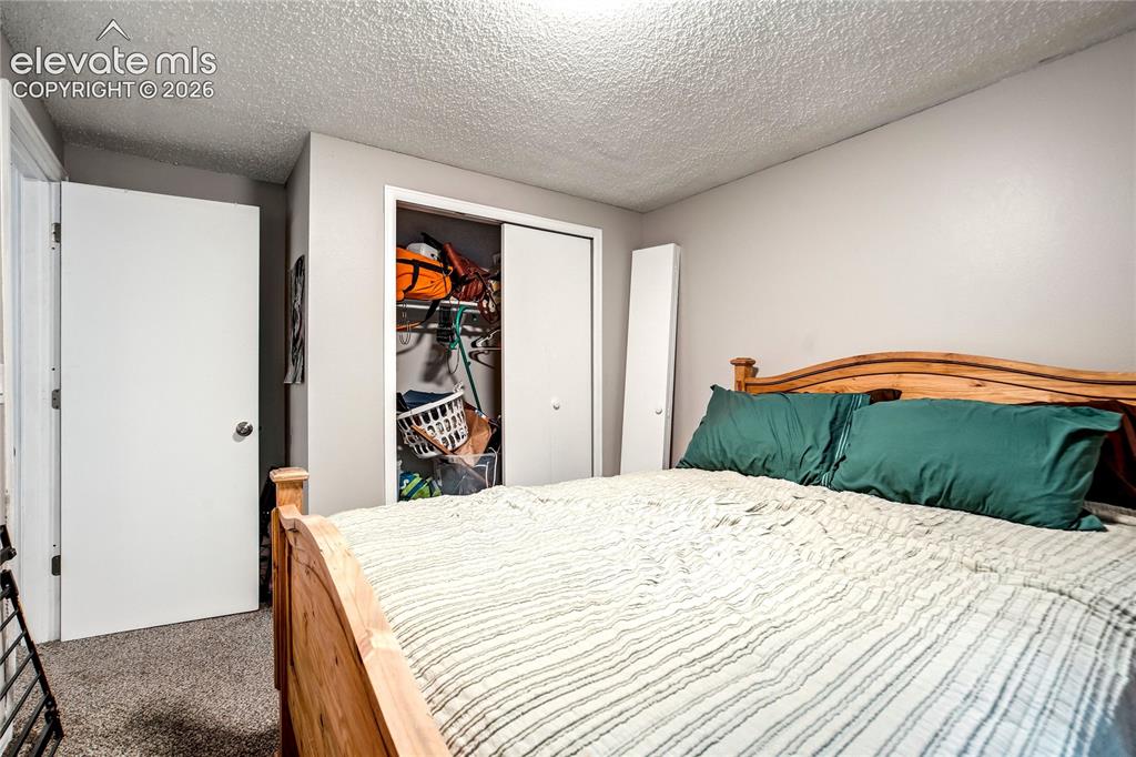 Image 45 of 50: Wall-to-wall carpeting, textured ceiling, and a built-in closet with slidin