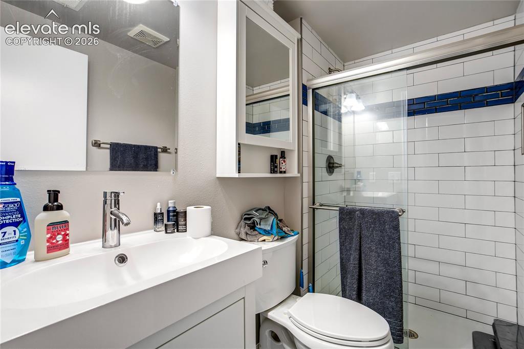 Image 46 of 50: White subway tile shower surround with blue accent tile, glass shower enclo