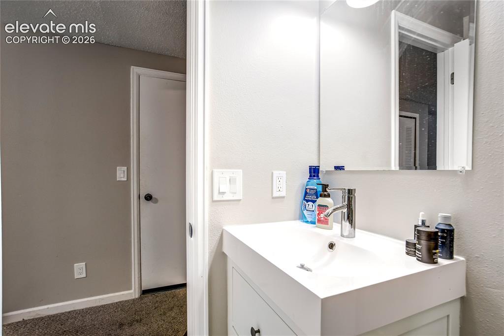 Image 47 of 50: Vanity featuring a white countertop and integrated sink, a chrome faucet, a