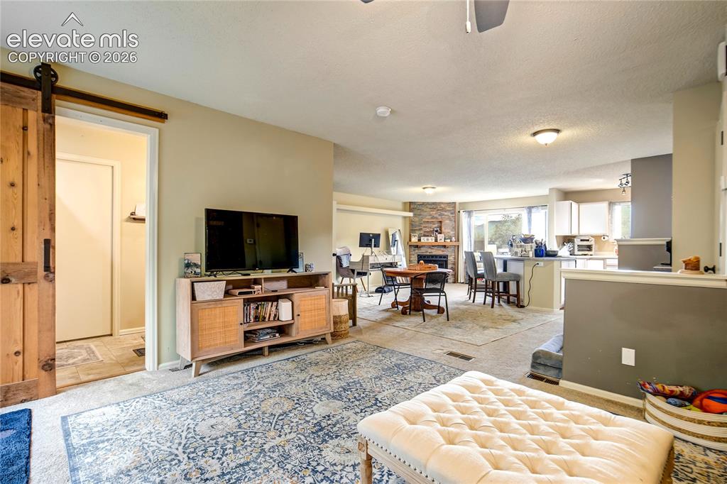 Image 7 of 50: Open-concept living area featuring a stone-clad fireplace and wood-finish s