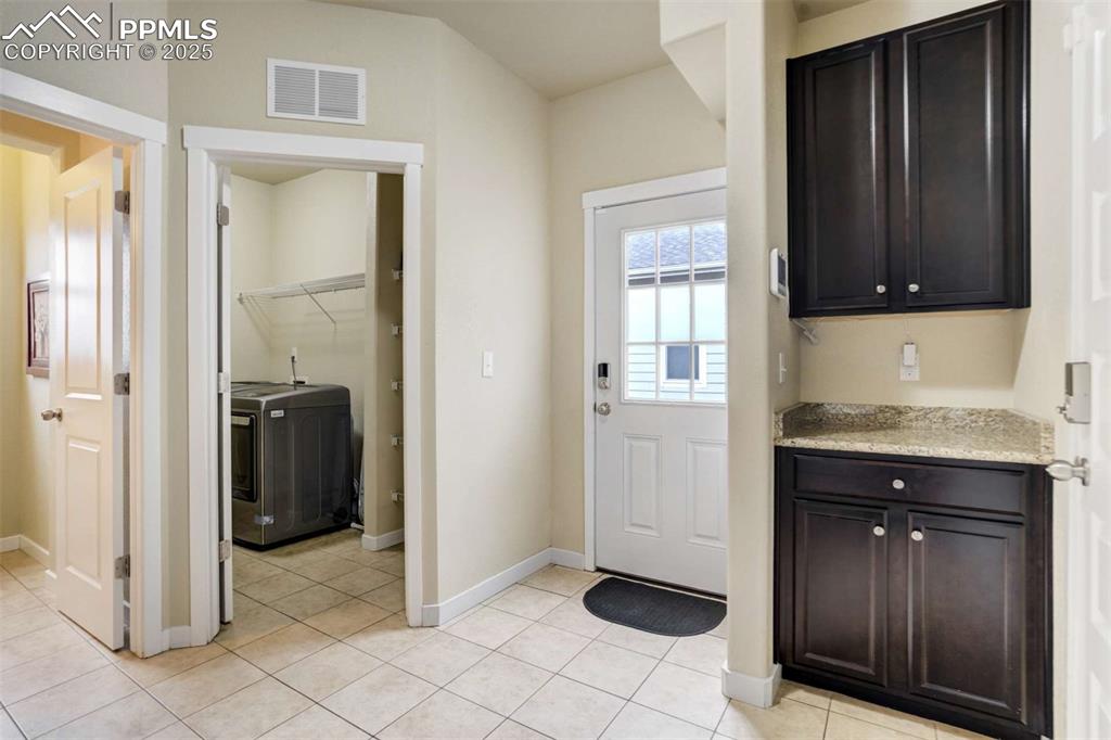 Image 20 of 50: Mudroom Area – Convenient drop zone with tile flooring, upper cabinetry, an