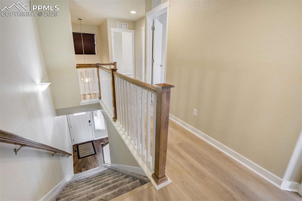 Image 23 of 50: Stairway & Landing – Bright upper-level landing with updated flooring, cont