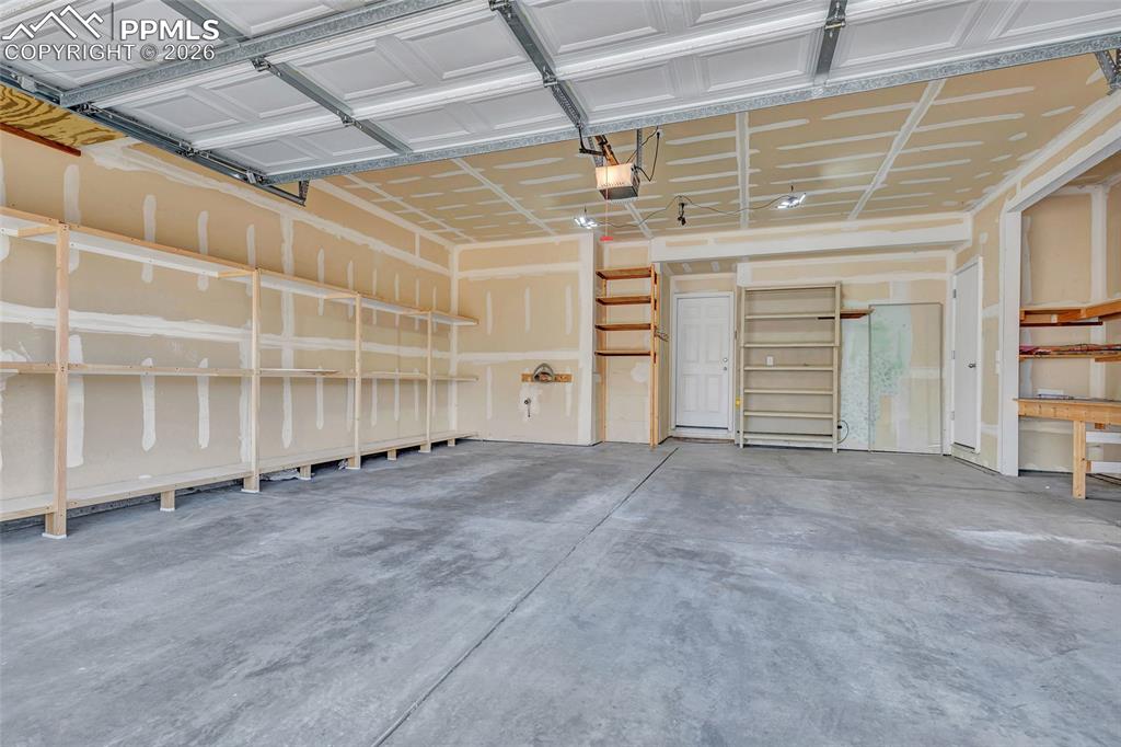 Image 18 of 38: 2 car garage with built-in storage and workbench area