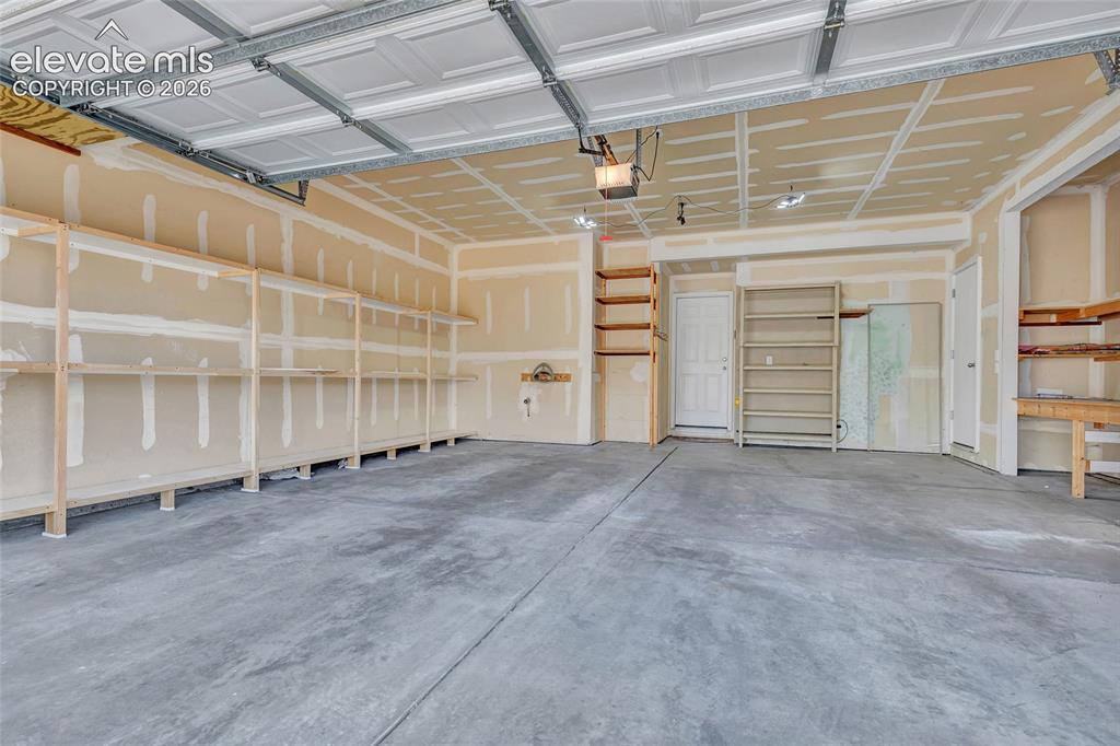Image 18 of 42: 2 car garage with built-in storage and workbench area
