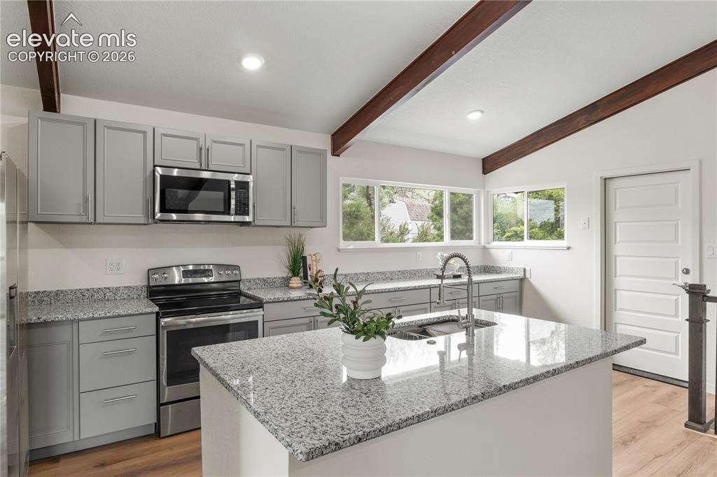 Image 10 of 30: Spacious kitchen featuring an island with an undermount sink, granite-style