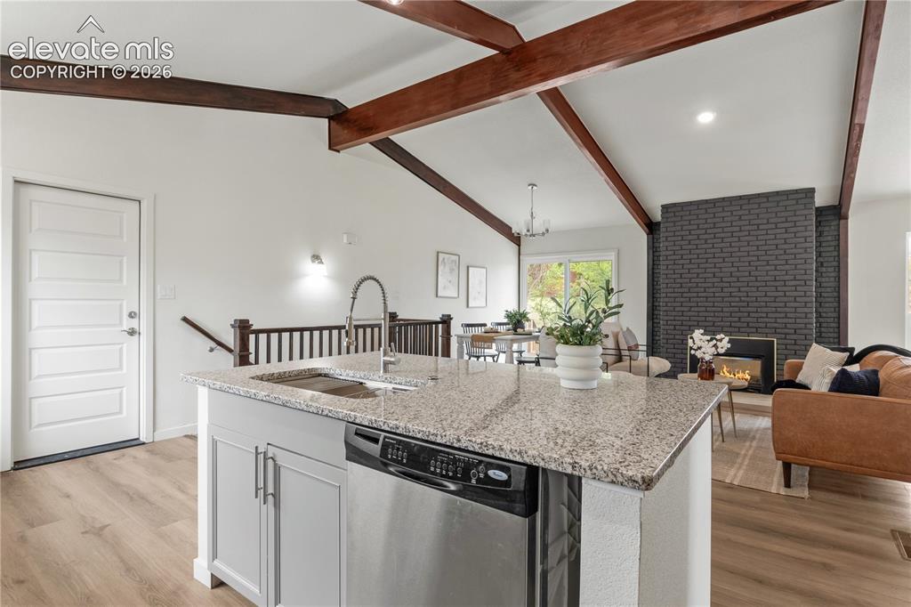 Image 11 of 30: Open-concept living area with vaulted ceilings and exposed wood beams