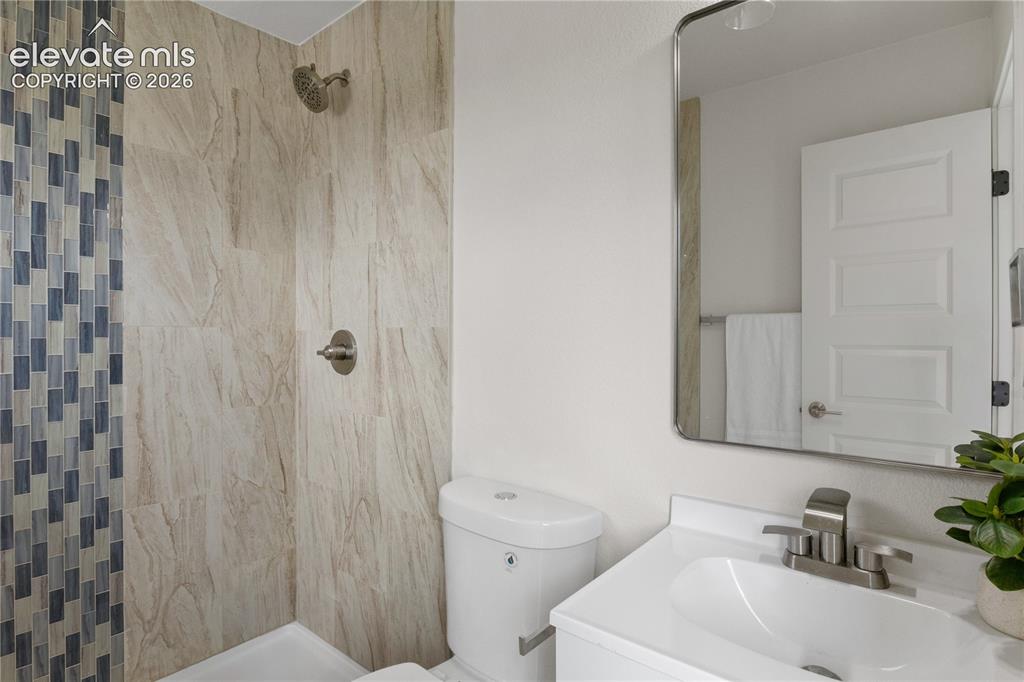 Image 14 of 30: Full bathroom featuring a walk-in shower with large format stone-look tile 
