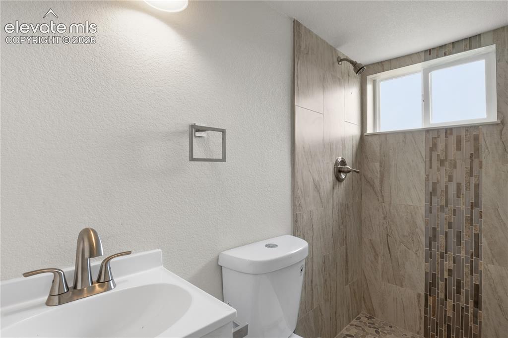 Image 17 of 30: Bathroom featuring a white vanity with brushed nickel fixtures, a toilet, a