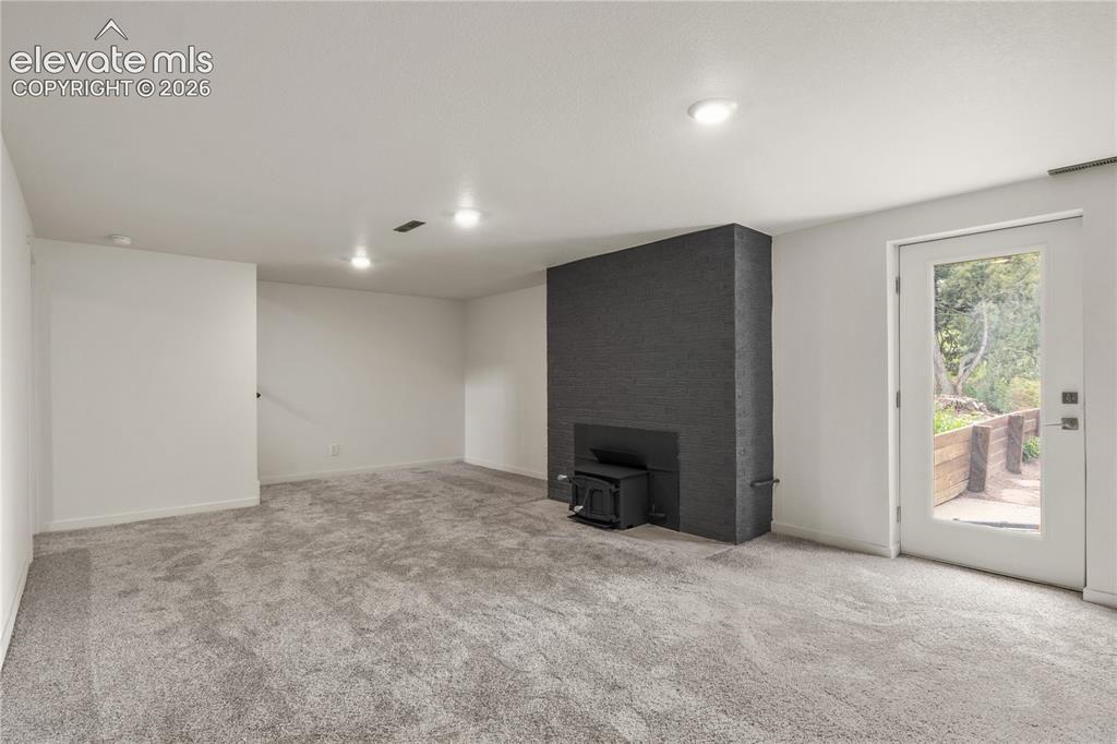 Image 18 of 30: Spacious room featuring light gray carpet, a black brick fireplace with a w
