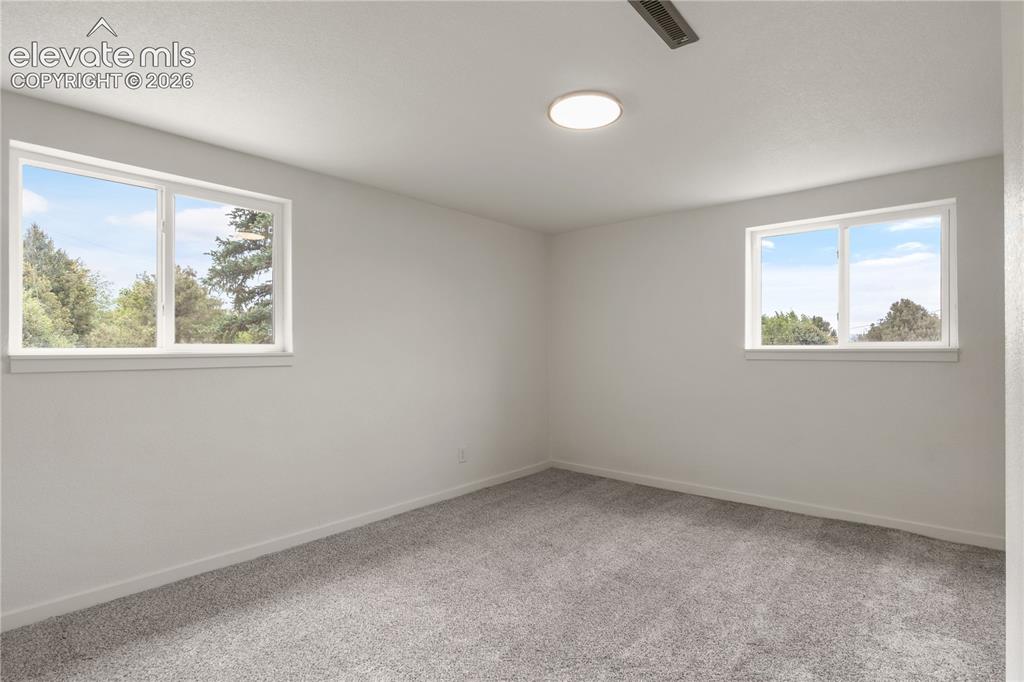 Image 20 of 30: Neutral-toned room featuring two framed windows, plush gray carpeting, whit