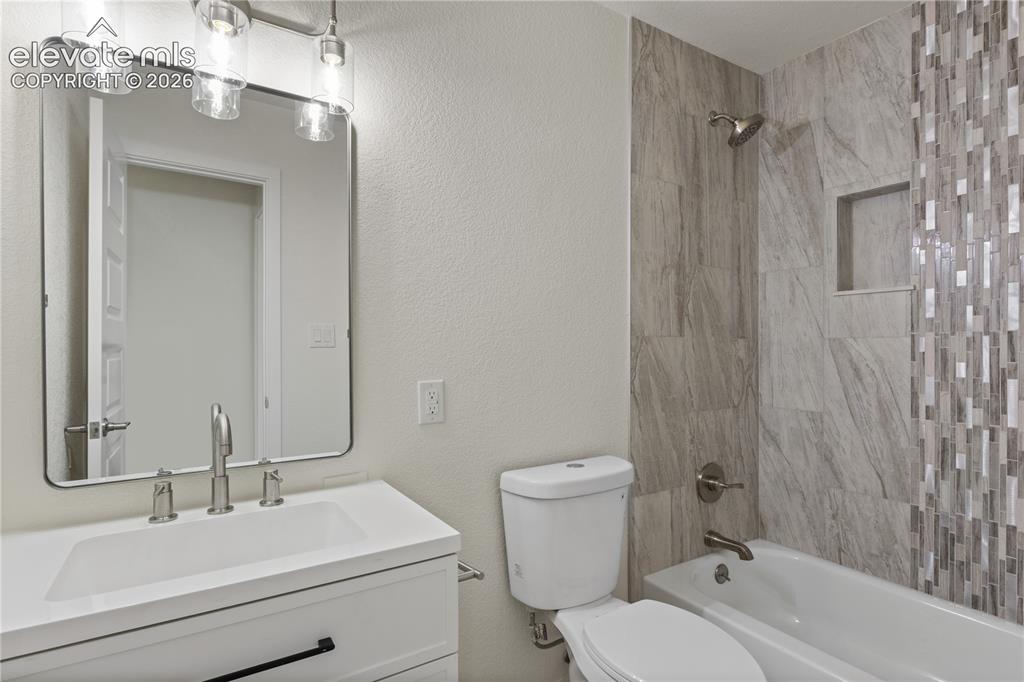 Image 22 of 30: Bathroom featuring a white vanity with integrated sink, brushed nickel fauc