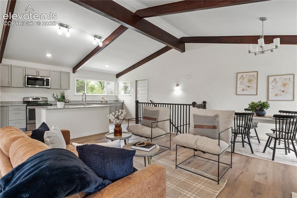 Image 5 of 30: Vaulted ceilings with exposed wood beams highlight this open-concept living
