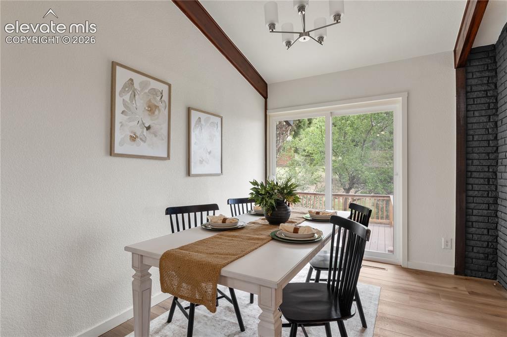 Image 7 of 30: Dining area featuring wood-finish flooring, a contemporary chandelier, a br