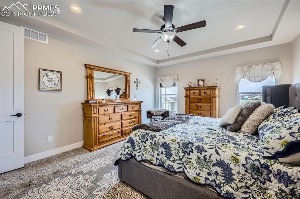 Image 11 of 27: Bedroom with a raised ceiling, carpet flooring, recessed lighting, baseboar