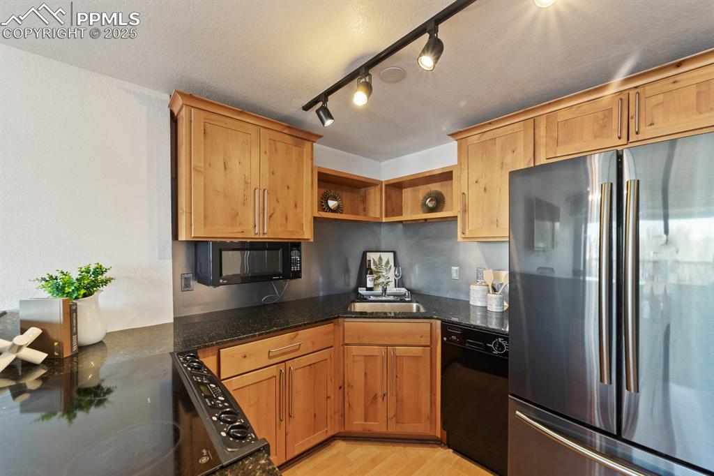 Image 10 of 32: Kitchen with black appliances, open shelves, dark stone countertops, light 