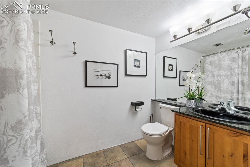 Image 15 of 32: Bathroom featuring toilet, vanity, and curtained shower