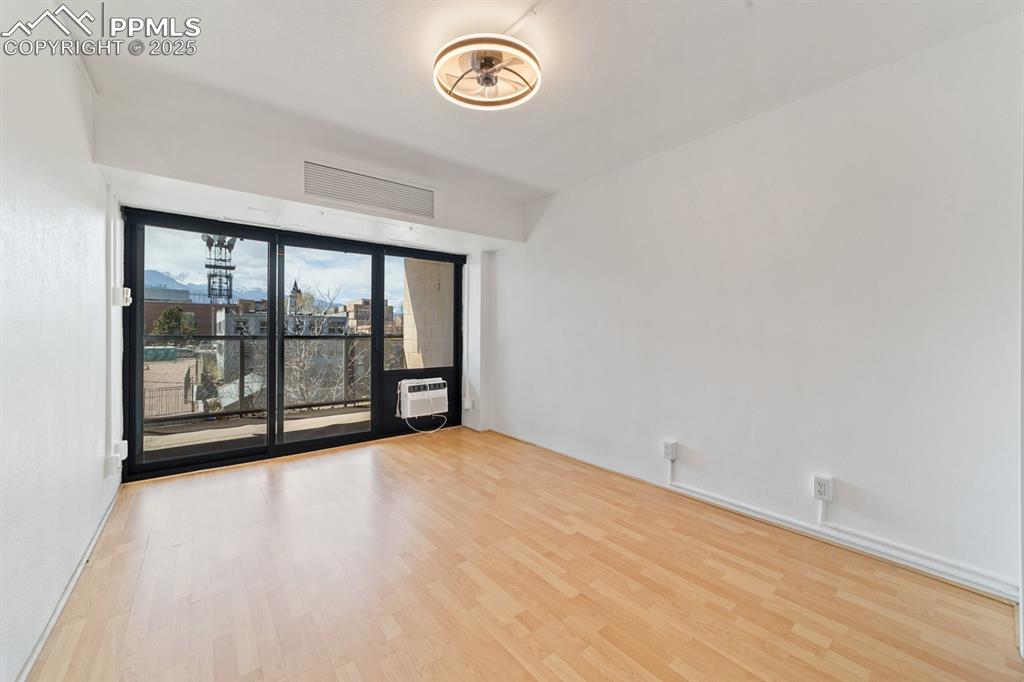 Image 17 of 32: Empty room featuring wood finished floors and an AC wall unit