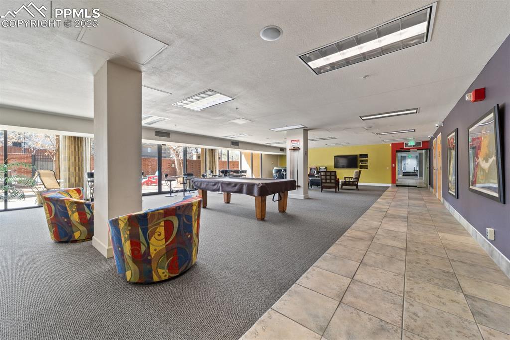 Image 24 of 32: Rec room with billiards table, carpet, tile patterned floors, a textured ce