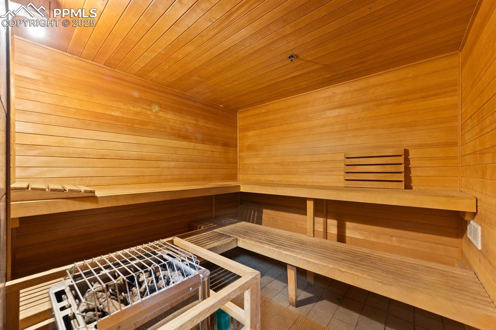 Image 29 of 32: Relaxing sauna featuring tile patterned floors, wooden walls, and wooden ce