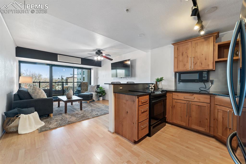 Image 5 of 32: Kitchen featuring black appliances, a peninsula, light wood finished floors