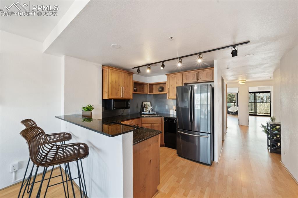 Image 9 of 32: Kitchen featuring black appliances, a peninsula, open shelves, and track li