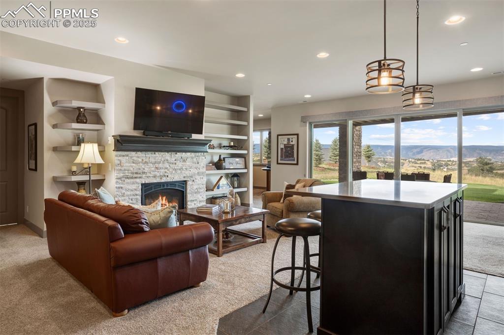 Image 16 of 31: Lower level recreation room with multiple sitting areas, fireplace, wet bar