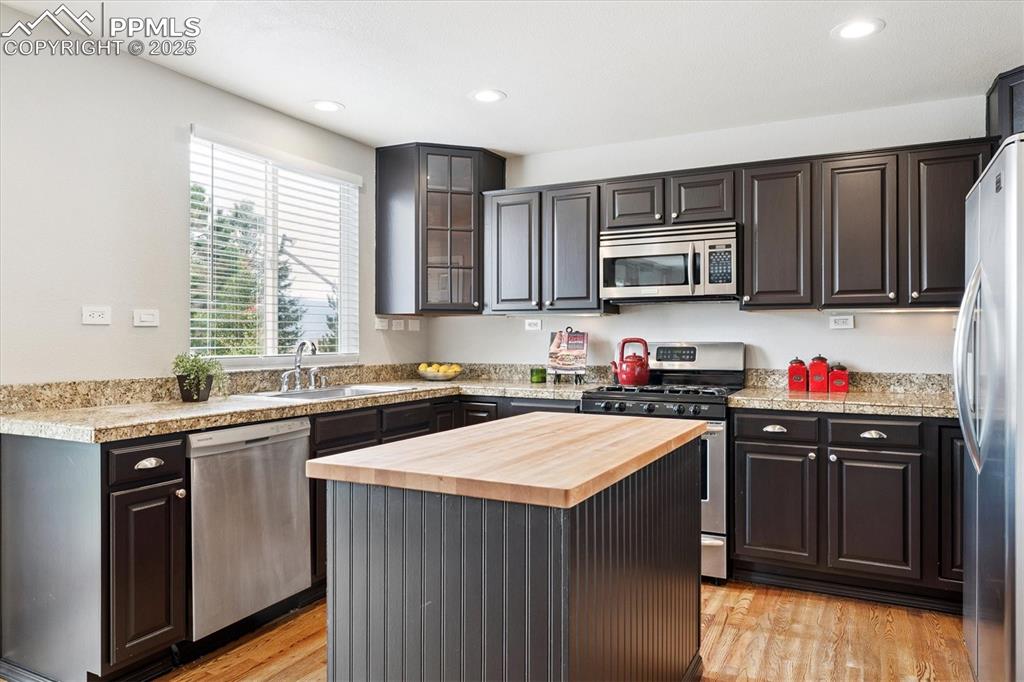 Image 12 of 40: Kitchen with butcher block countertops, stainless steel appliances, light w